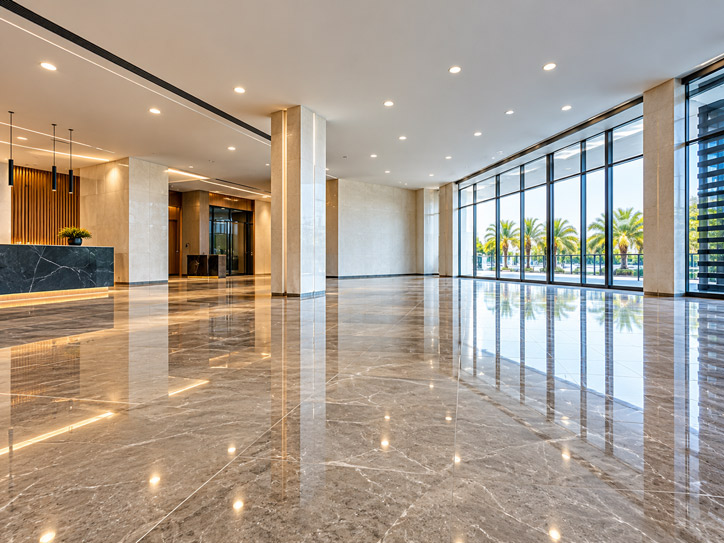 Commercial lobby with polished stone floors, a reception desk and floor-to-ceiling windows