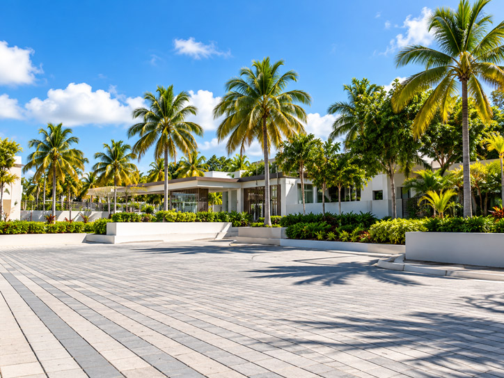 Landscaped commercial property with a paver plaza, planters and palm trees in front of a modern building